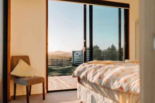 a bedroom with a bed and a sliding glass door at One Tree Hill Wilson prom and Ocean views in Toora