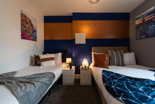 twee bedden in een kamer met blauwe en oranje muren bij Jesouth Exquisite Suite Dazzling Chic City Centre in Hull