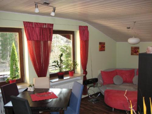 uma sala de estar com cortinas vermelhas, uma mesa e um sofá em Ferienwohnung Moser Brunhilde em Steingaden