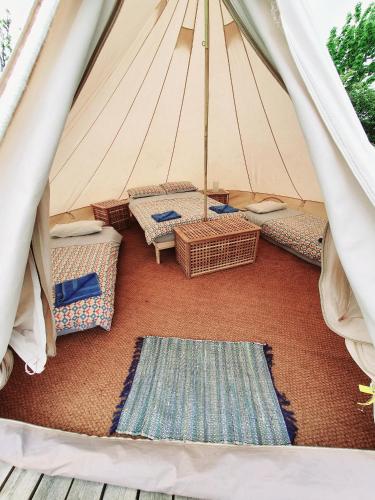 a tent with wicker chairs and a rug at Swanns Bridge Glamping in Limavady