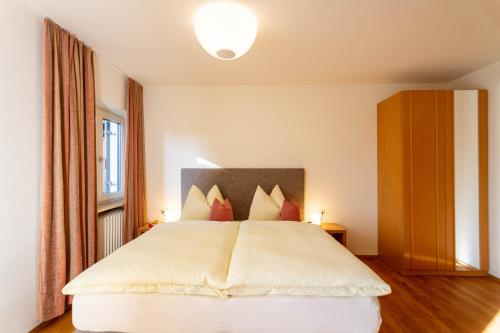een slaapkamer met een groot wit bed met rode kussens bij Haus Lohengrin Ferienwohnung 1 in Siusi