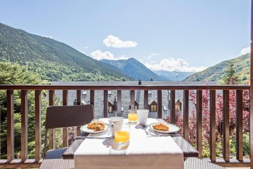 a table with plates of food and drinks on a balcony at Luderna - Apartamento con terraza Mirador Salardu in Naut Aran