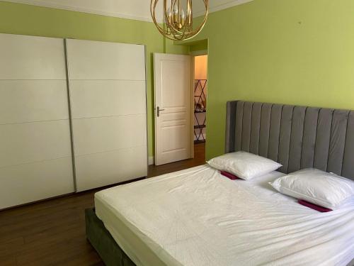 une chambre avec un lit avec des draps blancs et un lustre dans l'établissement Appartement Nice à proximité de la plage, à Nice