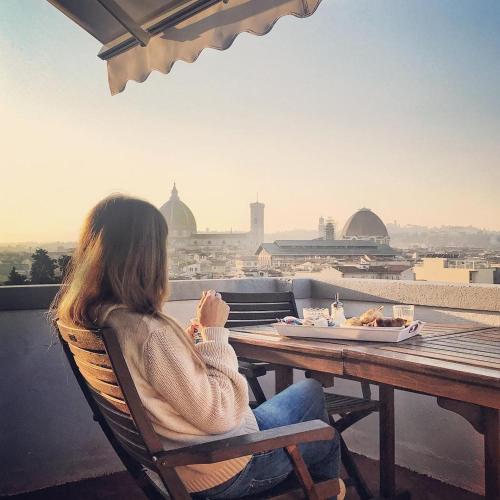 佛罗伦萨Artemente Florence B&B的坐在桌子上,望着一个城市的女人