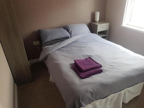 a white bed with a purple towel on it at Leecliff Guest House in Blackpool