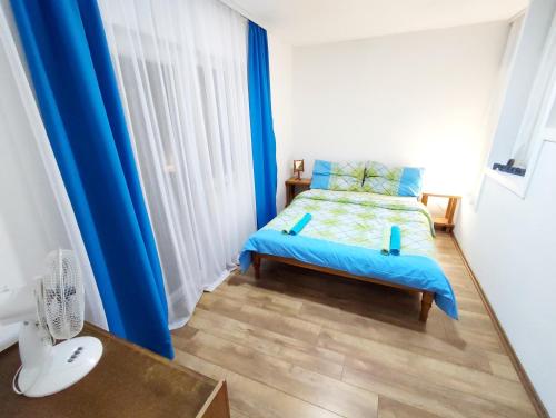 a bedroom with blue curtains and a bed with a wooden floor at Apartments and Rooms Minex in Trebinje