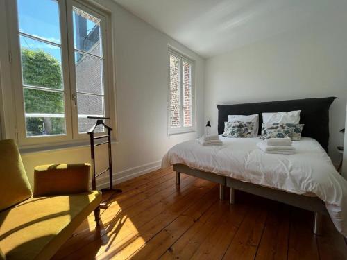 une chambre avec un grand lit et deux fenêtres dans l'établissement Maison familiale de ville à Etretat, à Étretat