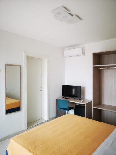 a bedroom with a bed and a desk and a mirror at Hotel Mare Blu in Torre dell'Orso