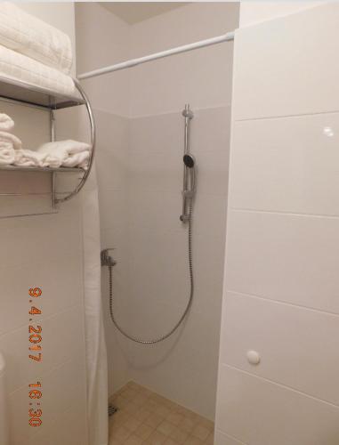 a shower in a white bathroom with a shower at Apartmani ljuta naranča in Zaton