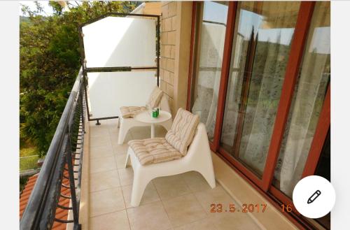 a balcony with two chairs and a table at Apartmani ljuta naranča in Zaton