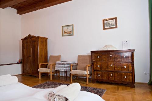 a bedroom with two beds and a dresser and chairs at Barta Pince Vendégház Mád in Mád