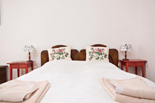 a bedroom with a white bed with two tables at Barta Pince Vendégház Mád in Mád