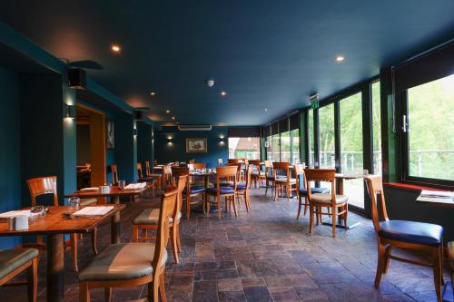 a restaurant with wooden tables and chairs and windows at Chevin Country Park Hotel & Spa in Otley