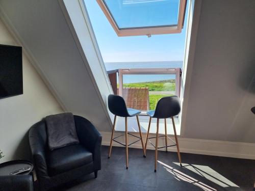 a room with two chairs and a table and a window at Ut Endt Vlieland in Oost-Vlieland