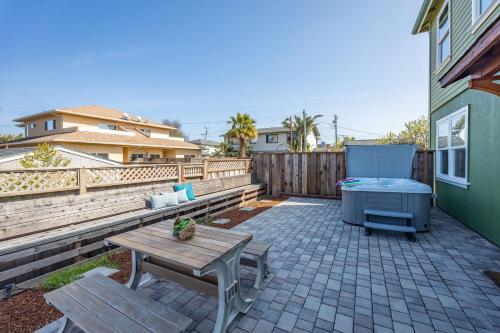 a patio with a wooden table and a bench at Beach Town Home wHot Tub - Walk to Beaches Downtown Activities and more in Half Moon Bay