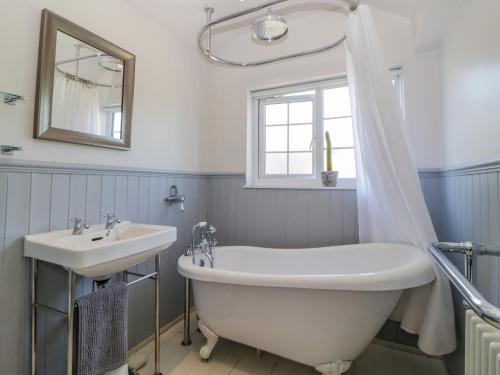 une salle de bain avec une baignoire et un lavabo dans l'établissement Burham Cottage, à Yelverton