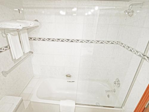 a white bathroom with a shower and a sink at The George Hotel by Saffron, Dubai Creek in Dubai