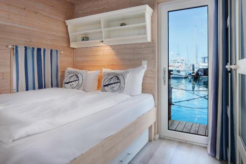 a bedroom with a bed with a view of the water at Hausboot - Stina in Heiligenhafen