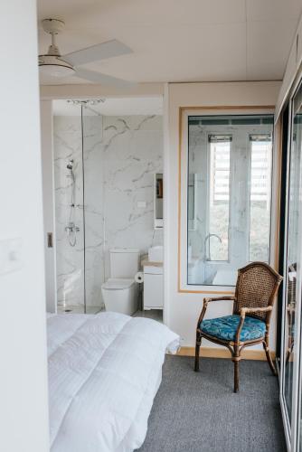 a bedroom with a bed and a chair and a shower at One Tree Hill Wilson prom and Ocean views in Toora