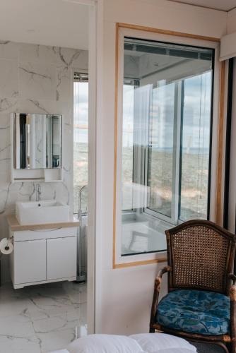a bathroom with a chair and a sink and a mirror at One Tree Hill Wilson prom and Ocean views in Toora