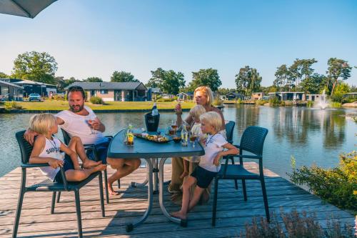 a family sitting at a table with a bottle of wine at EuroParcs Zilverstrand in Mol