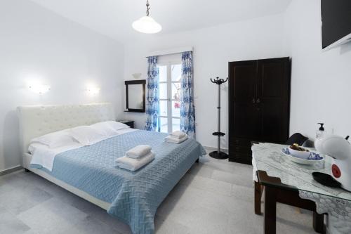a white bedroom with a bed and a table at Naxos Cave Suites in Stelida