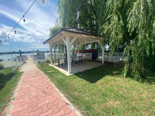 a gazebo with a picnic table next to the water at ElGringo Clisura Dunarii in Moldova Nouă