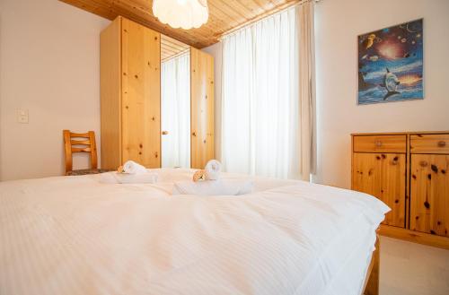 a bedroom with a large white bed with a window at Haus Padrun 5 in Arosa