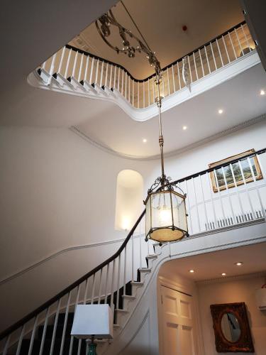 a staircase with a chandelier in a house at Stone Court House in Maidstone