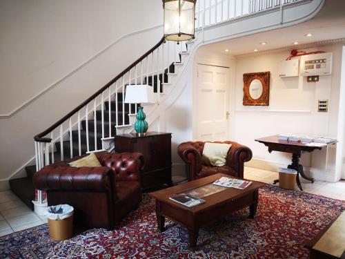 a living room with leather furniture and a staircase at Stone Court House in Maidstone