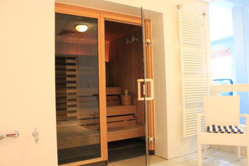 a glass shower door in a room with a chair at Haus Antje in Ahrenshoop
