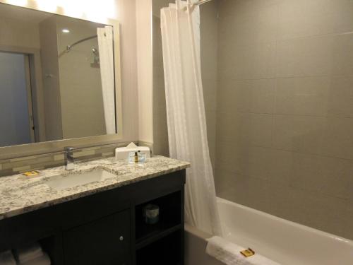 a bathroom with a sink and a shower and a tub at Best Western Plus Airdrie Gateway in Airdrie