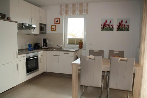 a kitchen with white cabinets and a table and chairs at Frida in Norddeich