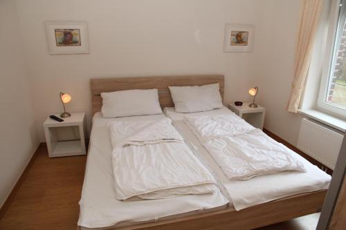 een slaapkamer met 2 bedden met witte lakens en een raam bij Friesenkoje in Norddeich
