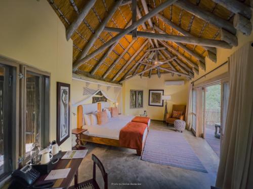 a bedroom with a bed and a desk in a room at Ongava Lodge in Okaukuejo