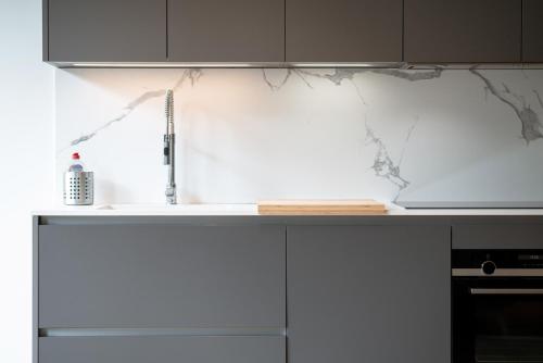 a kitchen with a white counter top and a sink at Lux City Hamilius - Modern & Spacious Apart w/View in Luxembourg