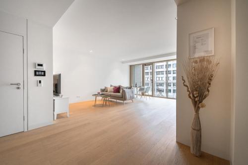 a living room with white walls and a vase of flowers at Lux City Hamilius - Modern & Spacious Apart w/View in Luxembourg