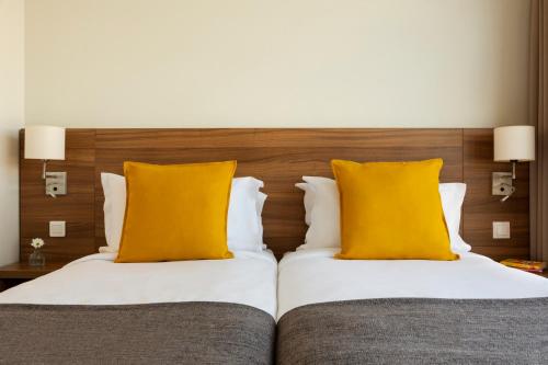two beds with yellow pillows in a hotel room at Citadines City Centre Lille in Lille