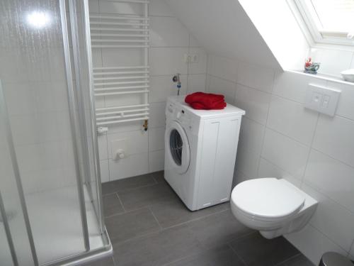 ein weißes Bad mit einem WC und einer Waschmaschine in der Unterkunft Kyana in Norden