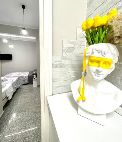 a statue of a head with yellow glasses and yellow flowers at Charm Airport in Reggio di Calabria