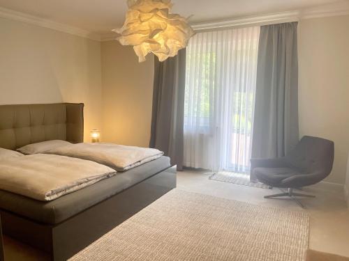 a bedroom with a bed and a chair and a chandelier at Ruhiges Landhaus am Wald mit Garten mit Schlafzimmer und Schlafnische in Aurich
