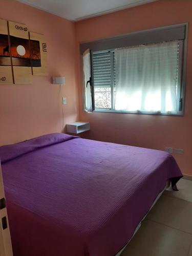 a bedroom with a purple bed and a window at Departamento de la Bahia in Bahía Blanca