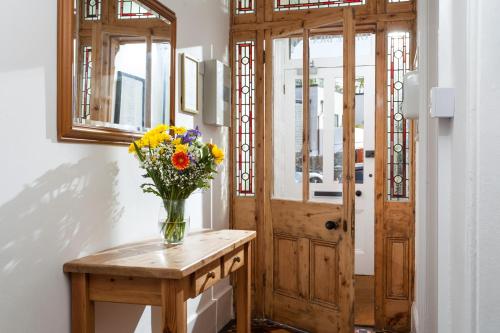 un jarrón de flores en una mesa junto a una puerta en The Olive Branch, en St Ives