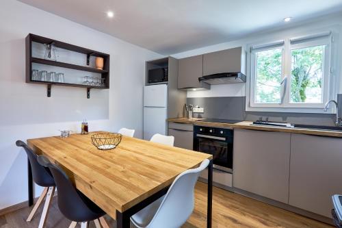 - une cuisine avec une table en bois et des chaises blanches dans l'établissement Domaine des amphores, à Faucon-de-Barcelonnette