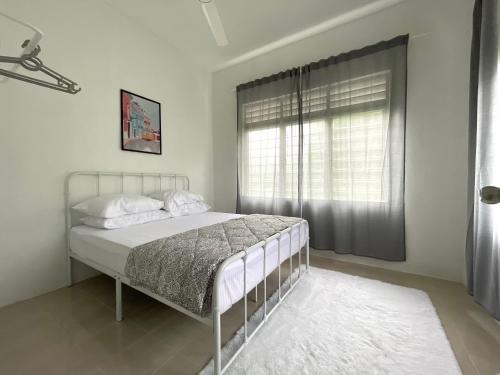 a white bedroom with a bed with a window at Cosy little home near to the town in Pasir Puteh