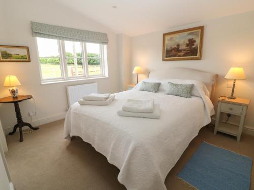 a bedroom with a large white bed with towels on it at Flagstone Cottage in Cheltenham