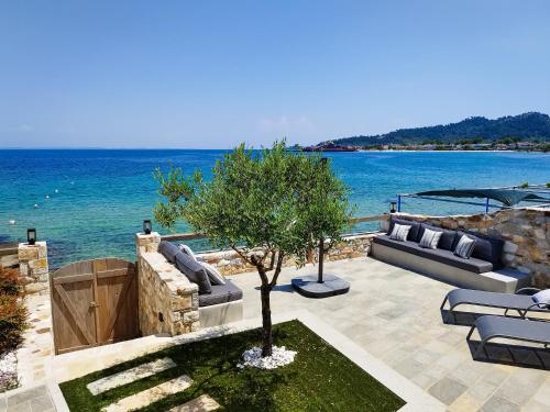 een patio met banken en een boom naast het water bij Aura di mare luxury house Thassos in Limenas