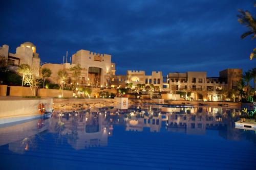 a swimming pool in front of a city at night at Pickalbatros The Palace Port Ghalib in Port Ghalib