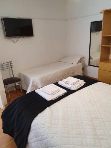 two beds in a room with a mirror and a tv at fucsia in Rosario