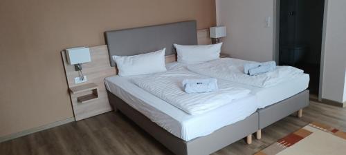 a bed with white sheets and blue pillows at Pension am Stern in Leipzig